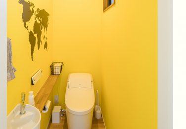 世界地図の入った黄色のクロスを使った、遊び心のあるトイレ　