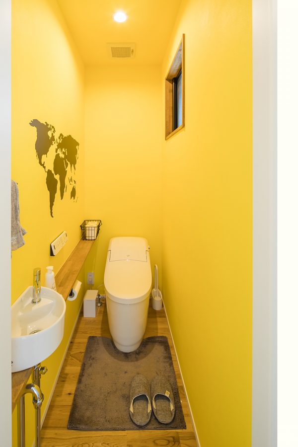 世界地図の入った黄色のクロスを使った、遊び心のあるトイレ　