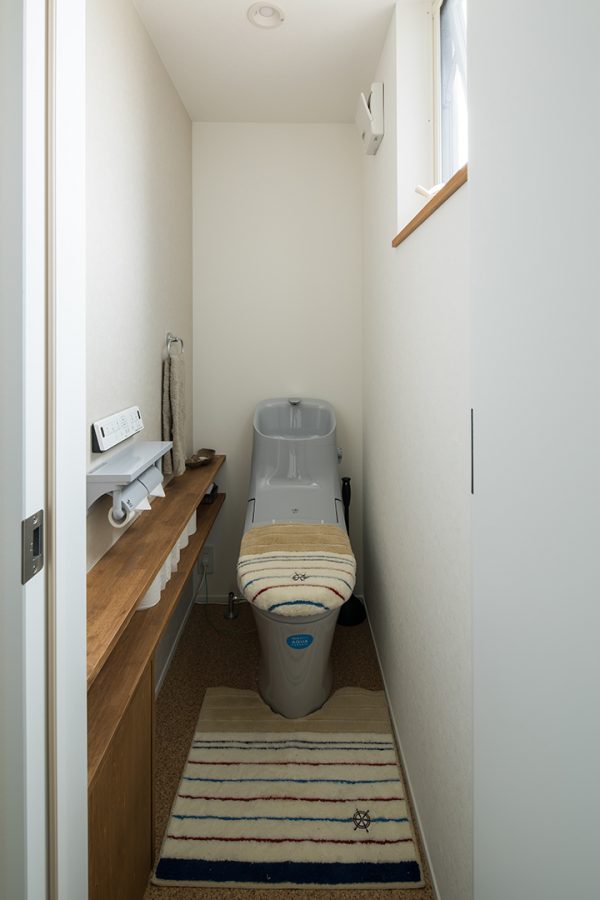 コルク風の床に造作棚のあるシンプルなトイレ　