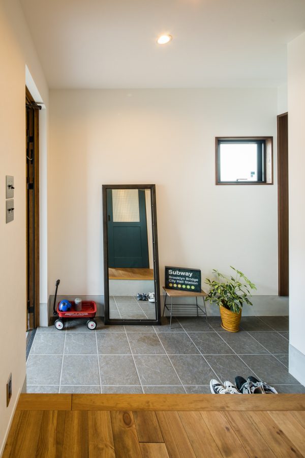 グレーのタイルに四角形の窓のあるシンプルな玄関