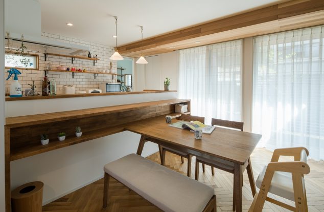 キッチンの腰壁に収納棚のついたダイニングスペース　