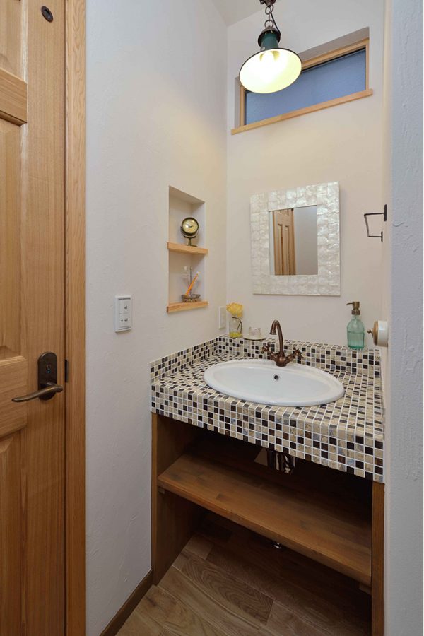 タイルの映える洗面台に飾り棚のあるかわいい洗面所　