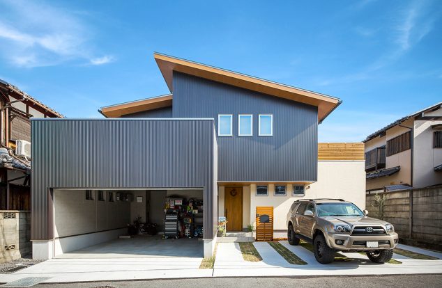 大きなビルドインガレージのある、ボックスと流れ屋根を合わせた外観　