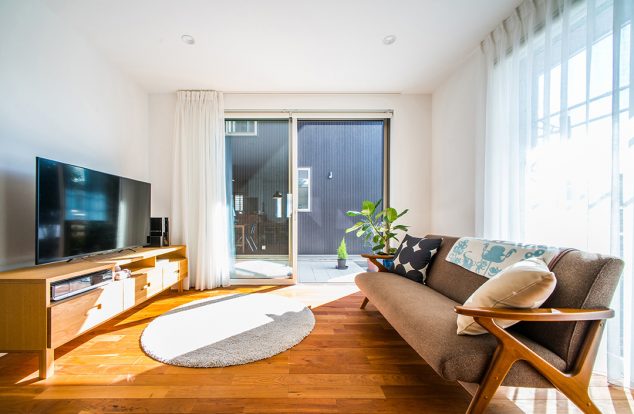 ブラックチェリーの飴色のフロアに中庭から光が注ぐリビング　