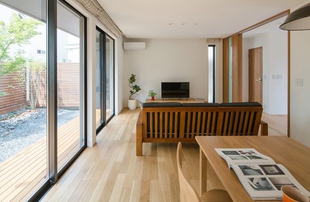 大きな掃き出し窓からウッドデッキのある庭の見えるリビング
