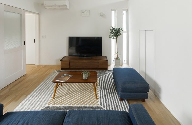 二つの縦長の窓から光が差し込むシンプルなリビング