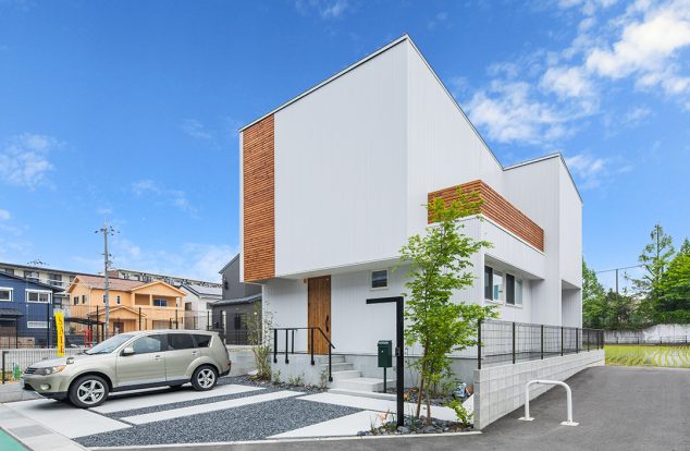 白の外壁に格子部分やバルコニーの木目が映える外観　