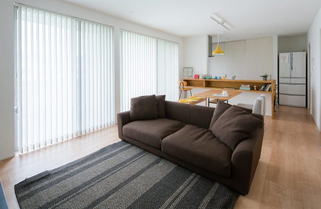 白色の室内に木の色のキッチンカウンターが映えるシンプルなリビング　　