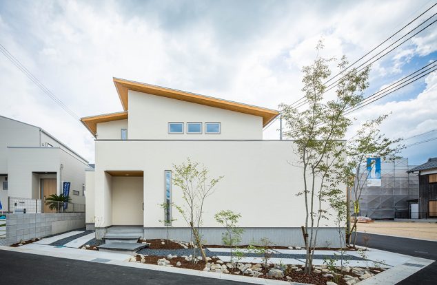 横長のボックス型に流れ屋根を組み合わせた白い外壁の外観