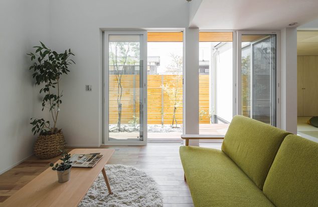 吹き抜けと掃き出し窓から光が入る、白壁のリビング　