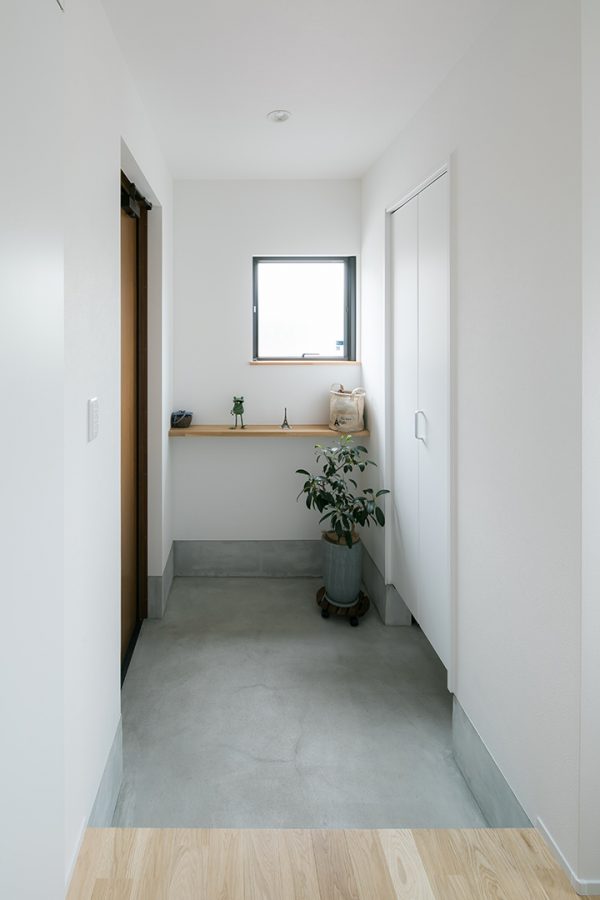 グレーと白で爽やな印象の、飾り棚のある玄関　