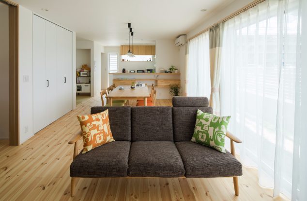 明るい色味で統一された空間に掃き出し窓から光が差し込むリビング　