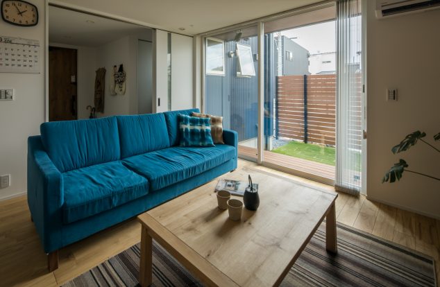 白で統一された室内にブルーのソファがアクセントのリビング