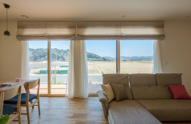 リビングの大開口から田園風景を臨めるやさしい色味のリビング　