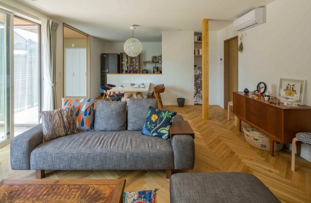 ヘリンボーンの床にシンボリックな化粧柱があるリビング