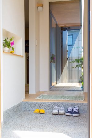 窓からのぞむ中庭と季節を感じるディスプレイのニッチに迎えられる玄関　