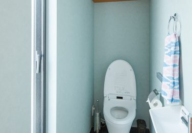 ネイビーのタイル調の床に造作棚のあるトイレ　
