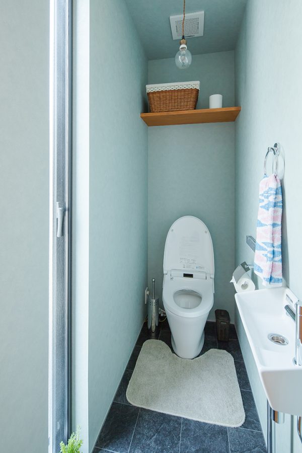ネイビーのタイル調の床に造作棚のあるトイレ　