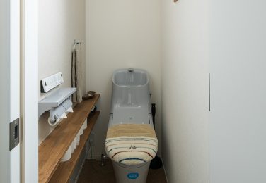 コルク風の床に造作棚のあるシンプルなトイレ　