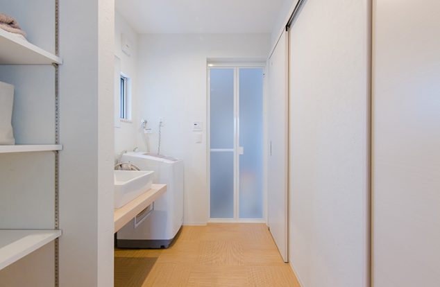 木目調の床に白の収納棚の洗面所　